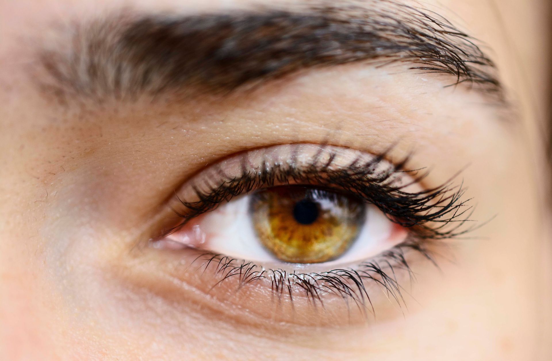 Detailed close-up image of a woman's hazel eye showcasing natural beauty and features.